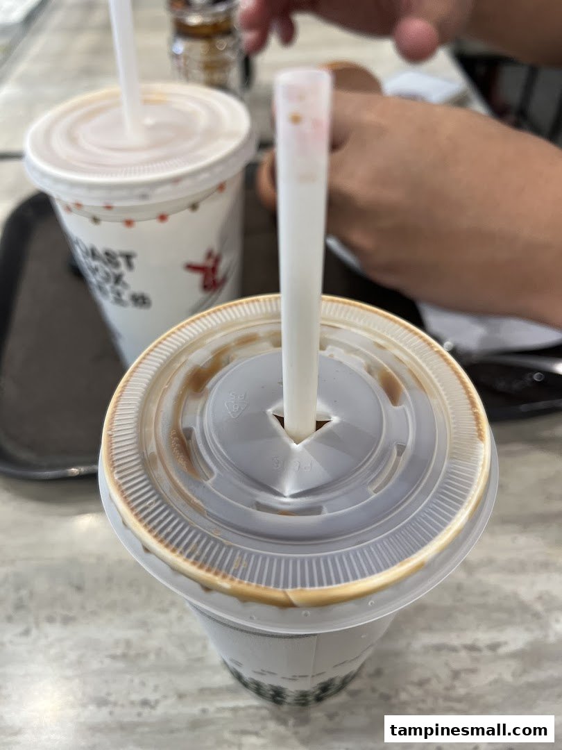 Two beverages, one with a straw, on a table inside Toast Box.