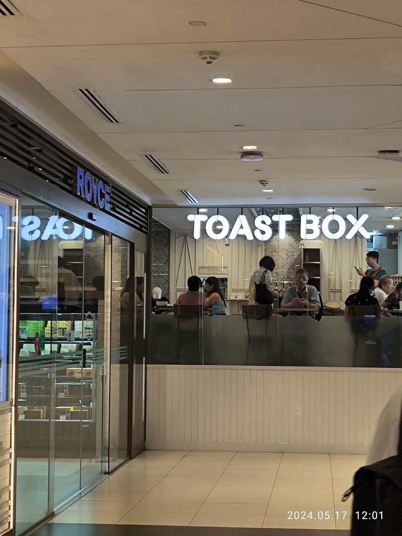 Interior view of Toast Box with customers at the counter, adjacent to a Royce shop entrance.