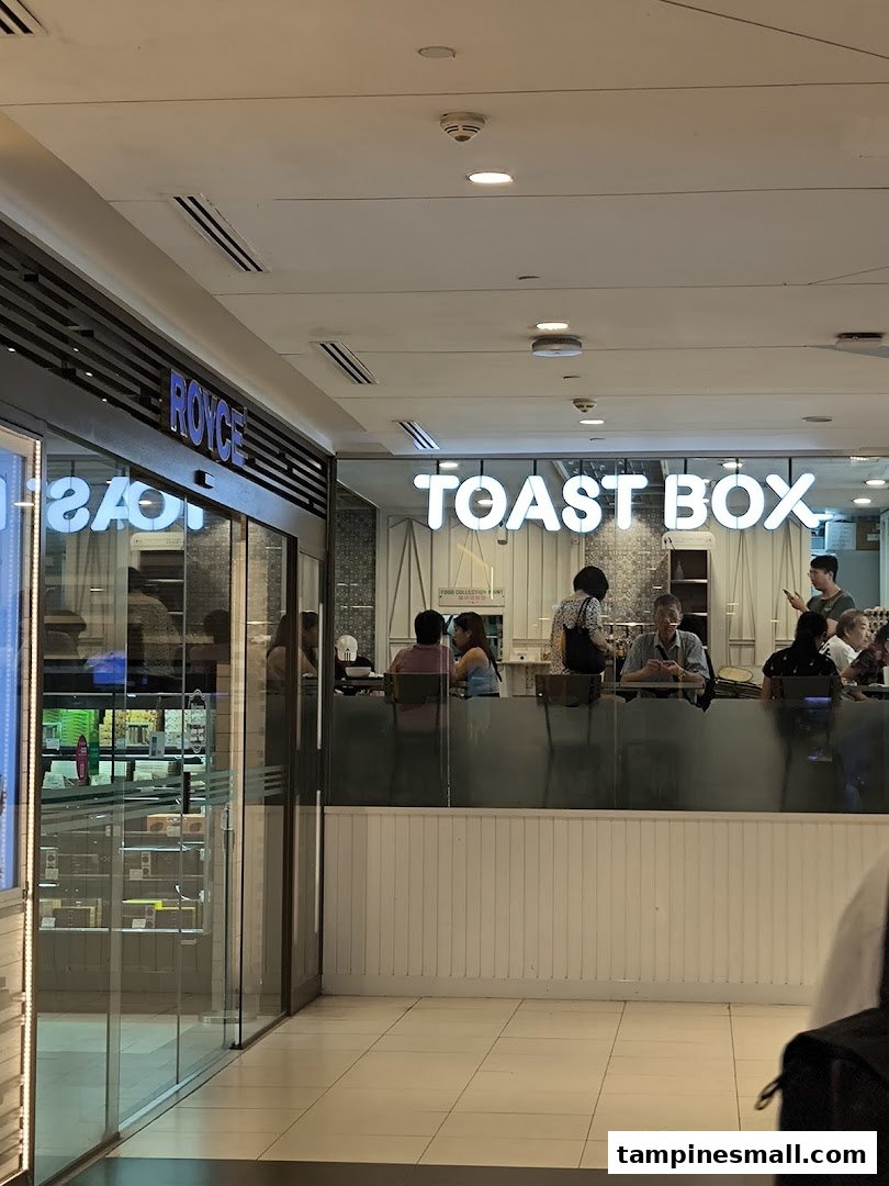 Interior view of Toast Box with customers at the counter, adjacent to a Royce shop entrance.