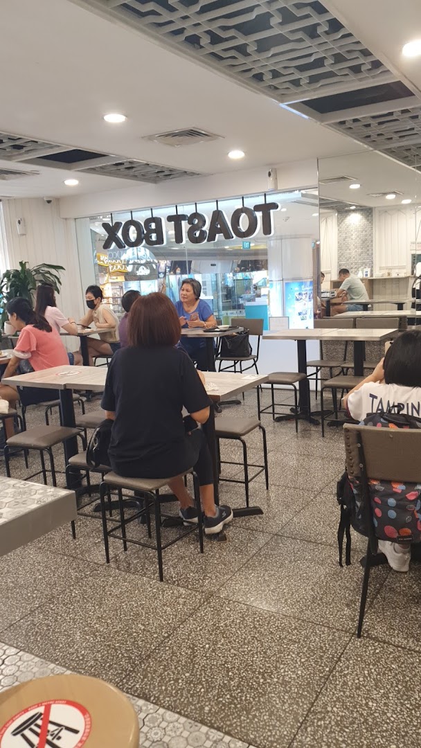 Customers enjoying a meal inside Toast Box, with the shop's name visible through the glass.