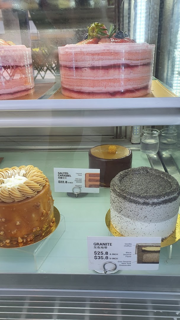 A display case showcasing various delicious cakes, including strawberry, salted caramel, and granite flavors.