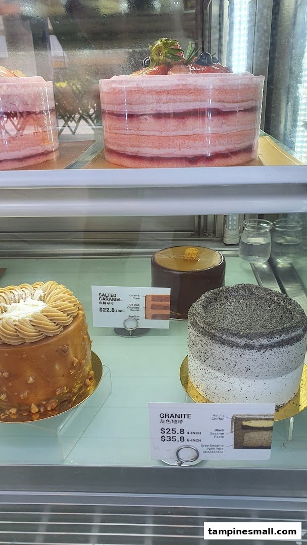 A display case showcasing various delicious cakes, including strawberry, salted caramel, and granite flavors.