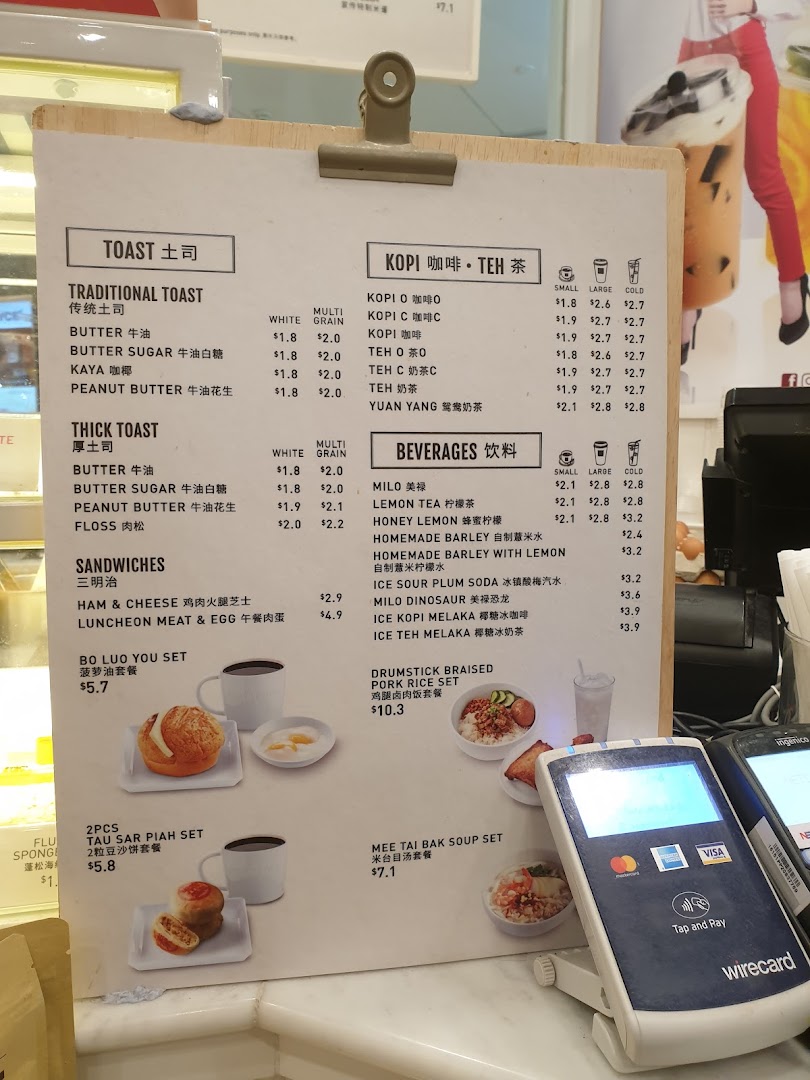 A detailed menu board displaying various toast, coffee, tea, beverages, sandwiches, and set meals with prices.