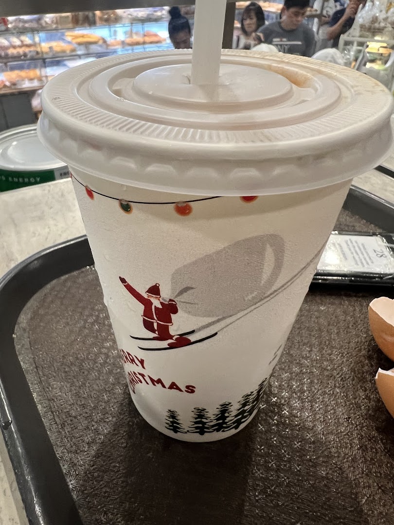 A festive drink cup with a Santa skiing design on a tray, inside a cafe setting.