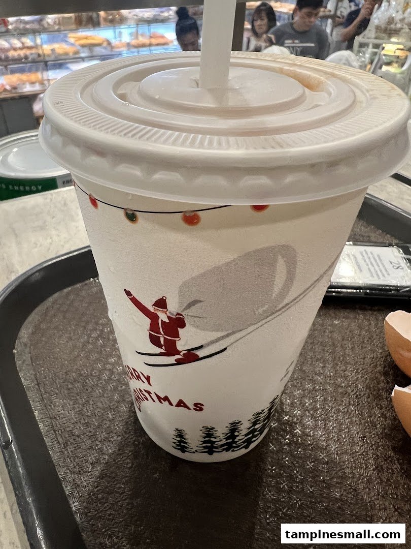 A festive drink cup with a Santa skiing design on a tray, inside a cafe setting.