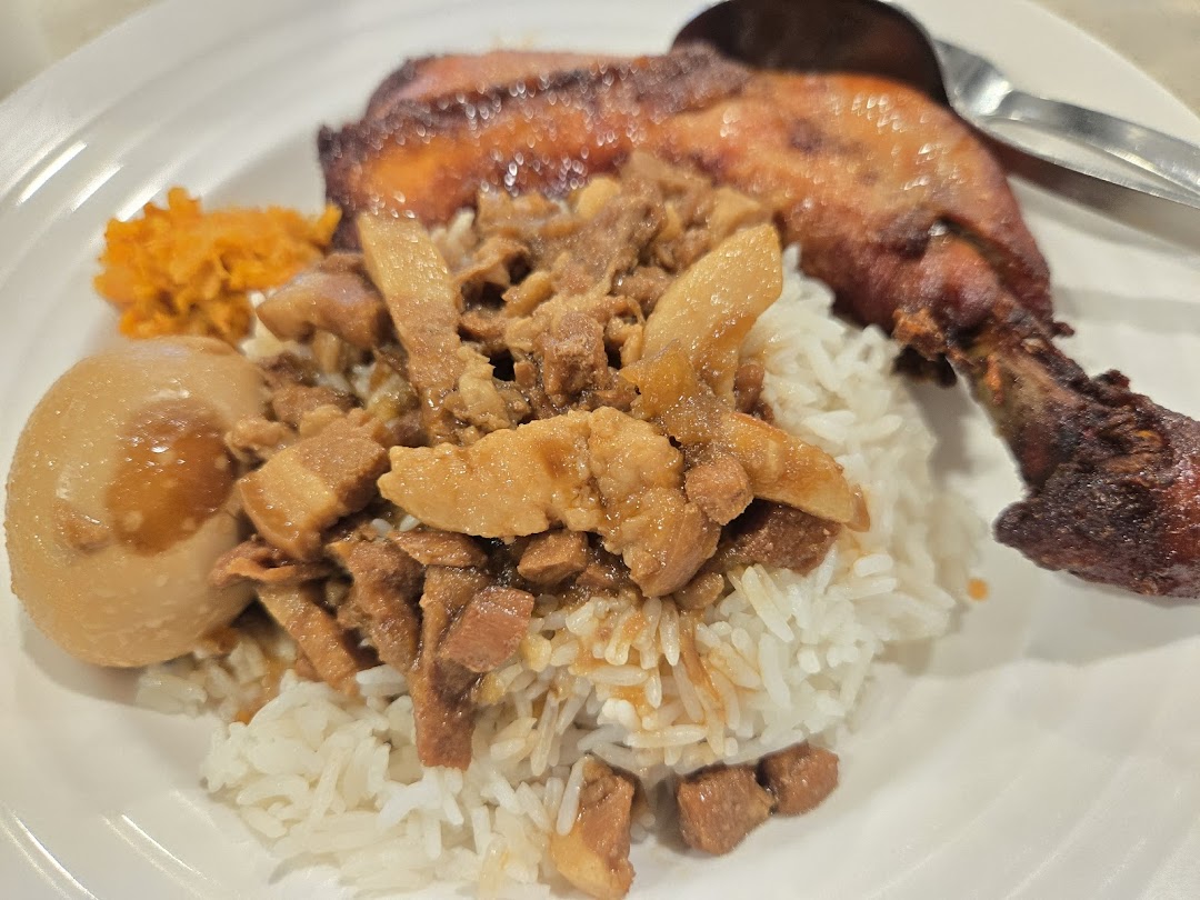 A delicious plate featuring rice, braised pork, a braised egg, and a crispy chicken drumstick.