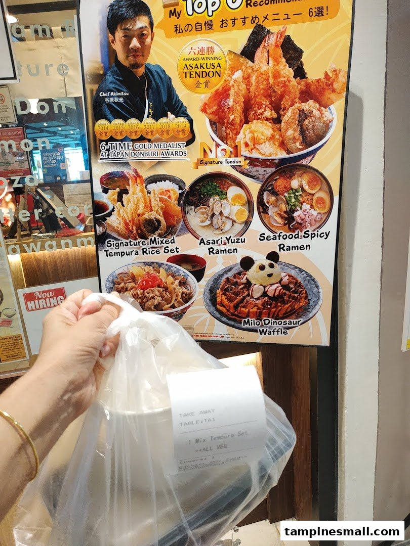 A customer holds a takeaway bag in front of Tokyo Shokudo's award-winning menu display.