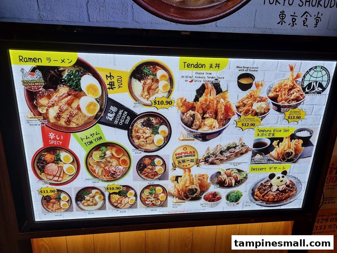 A brightly lit menu board showcasing various Japanese ramen, tendon, and side dishes with prices.
