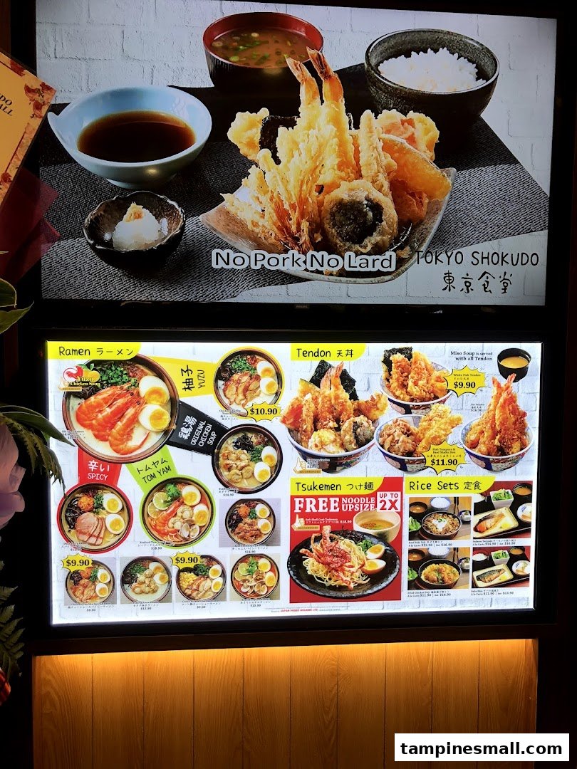 A brightly lit menu board showcasing various Japanese dishes like ramen, tendon, and rice sets.