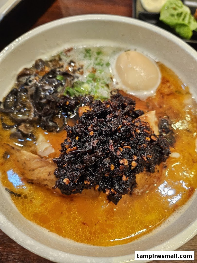A close-up of a vibrant ramen or noodle dish with a rich broth, chili oil, a soft-boiled egg, and mushrooms.