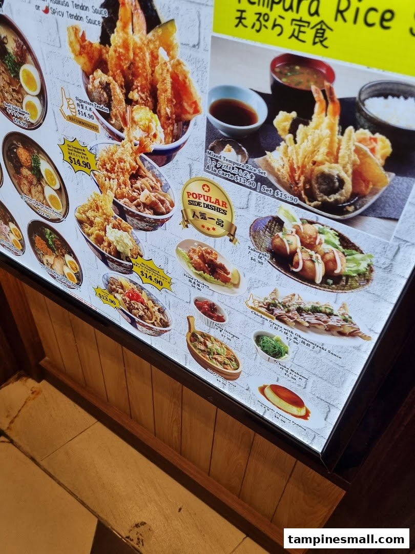 A brightly lit display board showcasing various Japanese dishes, including tempura, ramen, and popular side dishes with prices.