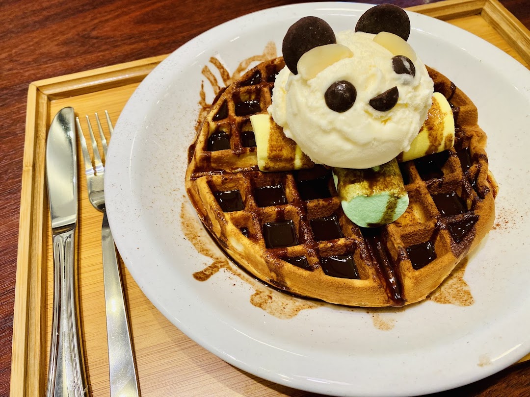 A delightful waffle topped with a panda-themed ice cream scoop and chocolate sauce.