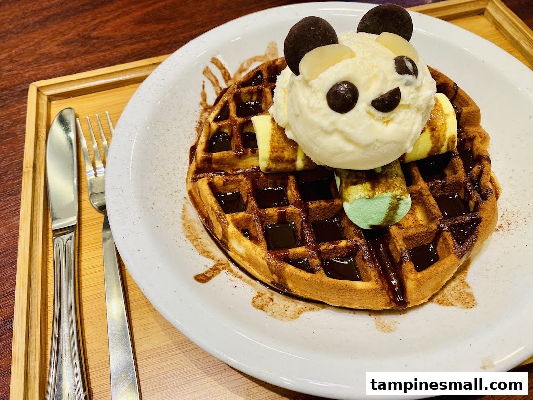 A delightful waffle topped with a panda-themed ice cream scoop and chocolate sauce.