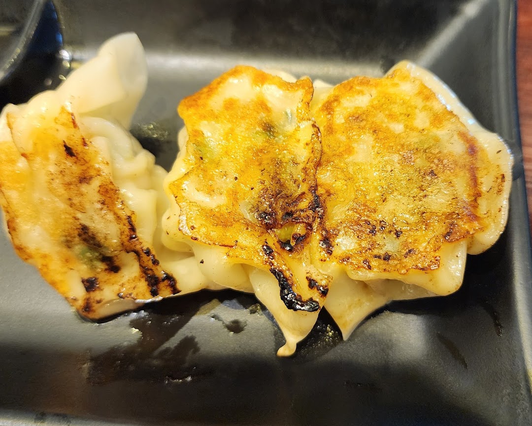 Close-up of golden-brown pan-fried gyoza served on a black plate.