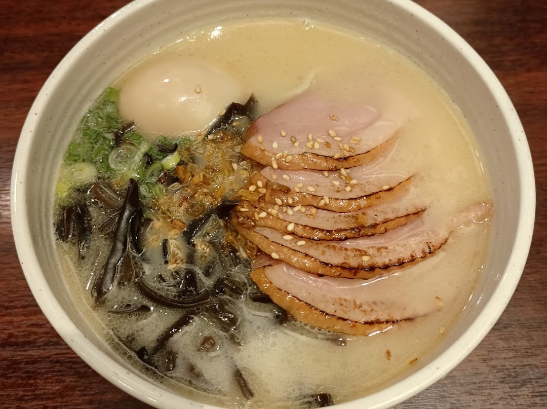 A close-up of a delicious bowl of ramen with sliced pork, a soft-boiled egg, and green onions.