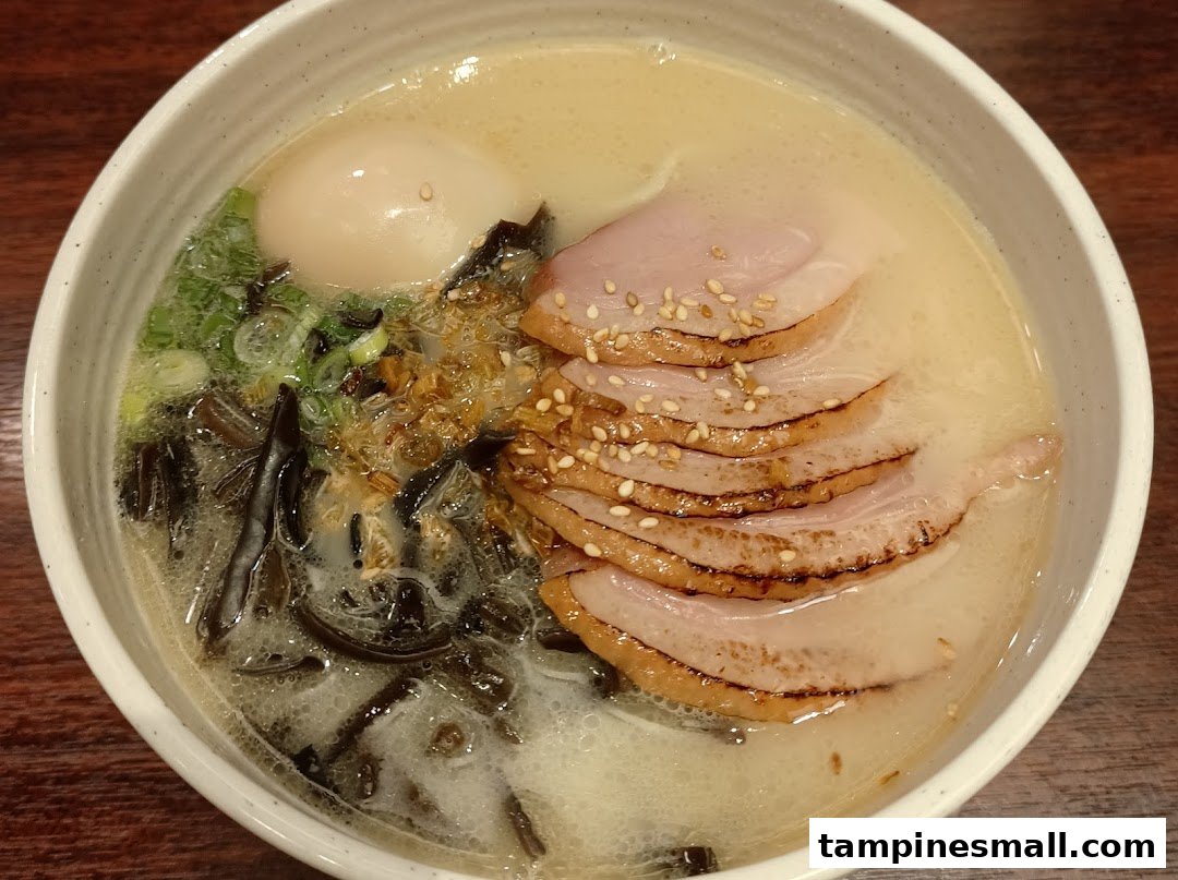 A close-up of a delicious bowl of ramen with sliced pork, a soft-boiled egg, and green onions.