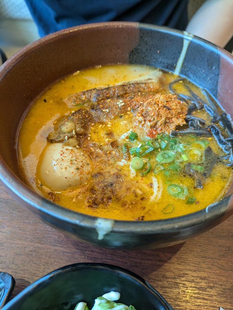 A close-up of a vibrant bowl of ramen with rich broth, an egg, meat, and fresh green onions.