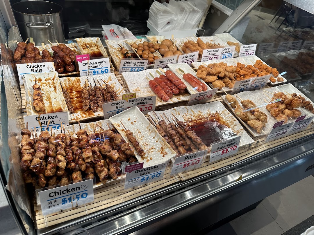A vibrant display of various Japanese-style skewers and fried items in a retail food counter.