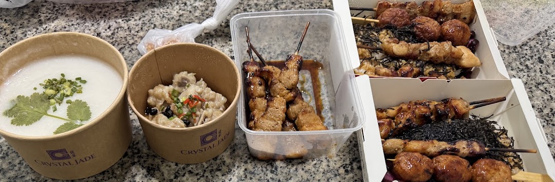 A collection of takeout dishes, including congee, a savory meat dish, and various grilled skewers, on a countertop.
