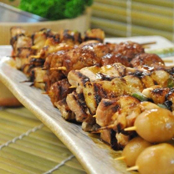 A close-up of various grilled skewers, including chicken and possibly quail eggs, on a serving platter.