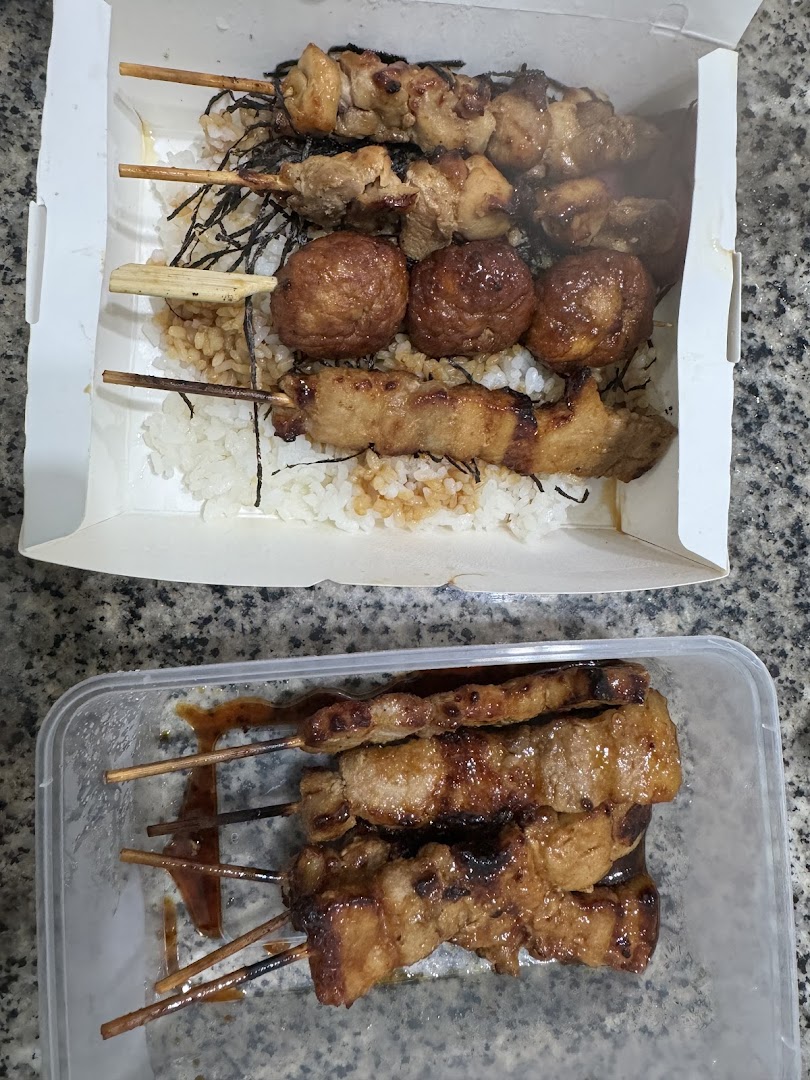 Delicious grilled skewers with rice in a takeaway box and an additional container of skewers.