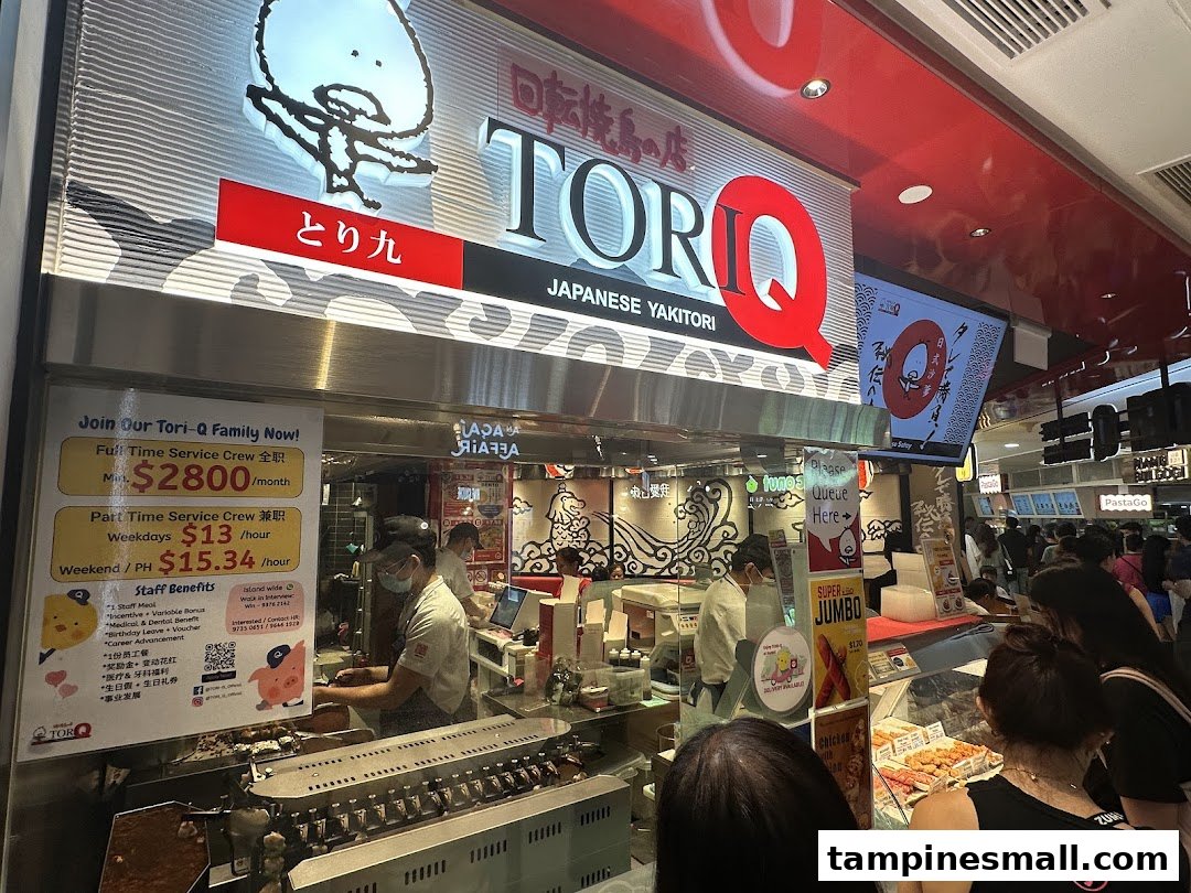 The bustling front of TORI-Q, a Japanese yakitori shop, with staff preparing food and customers queuing.