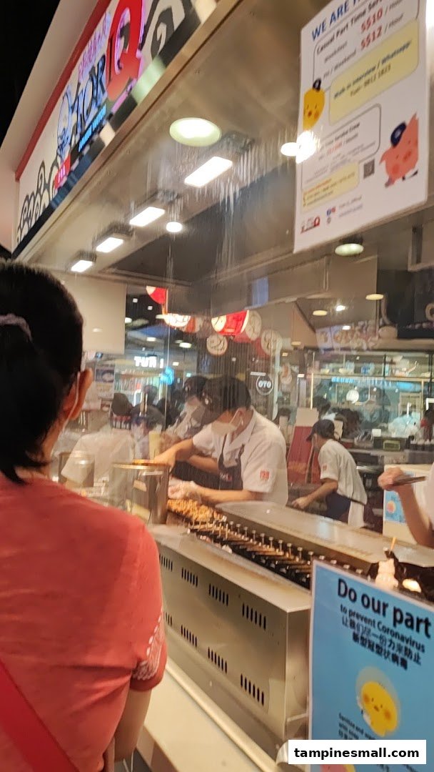 Staff prepare delicious skewers behind the counter at TORI-Q, showcasing fresh cooking.