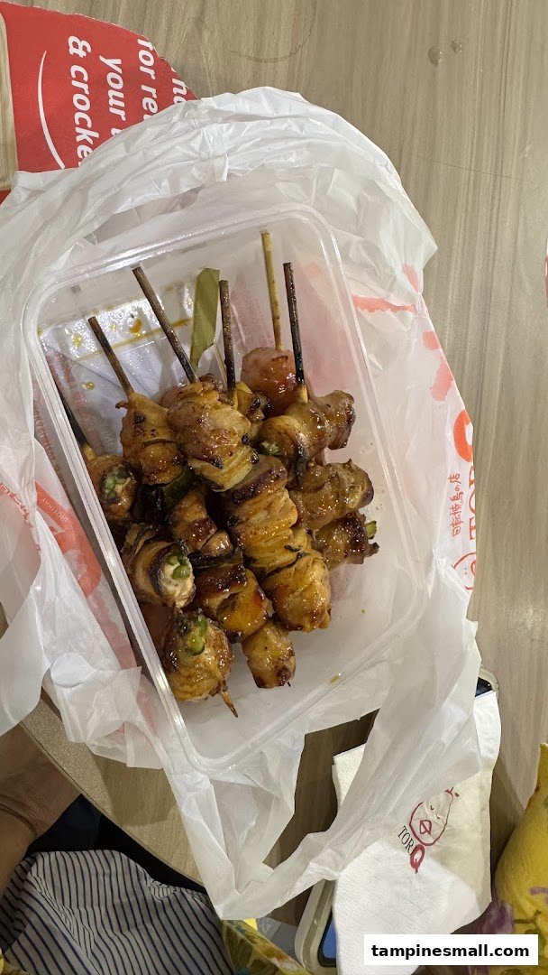 A plastic container filled with various grilled skewers, including chicken and vegetables, inside a plastic bag.