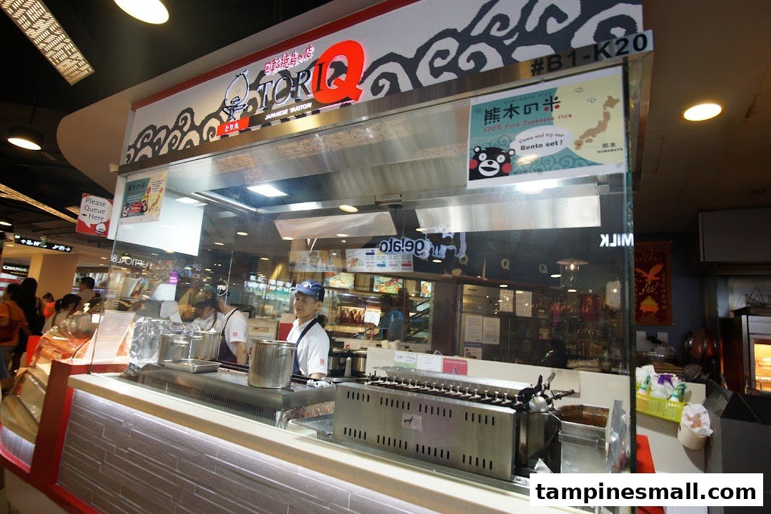 A bustling TORI-Q Japanese Yakitori stall with staff preparing food and a prominent brand sign.