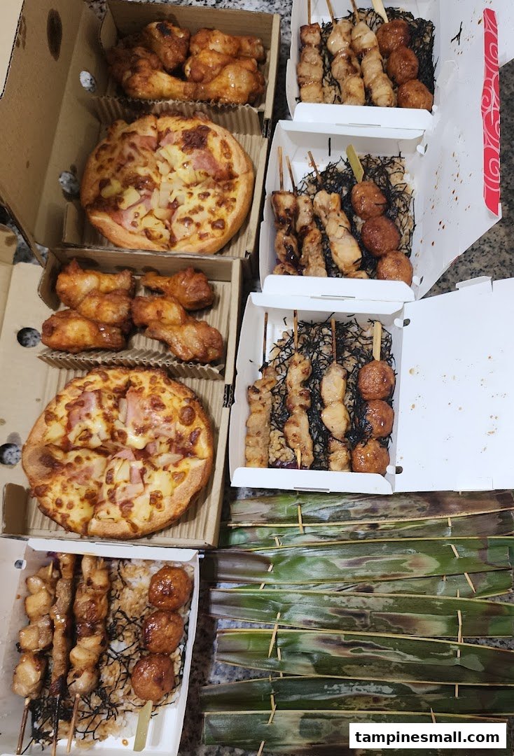 A spread of delicious takeout food including pizzas, chicken wings, and yakitori skewers in boxes.