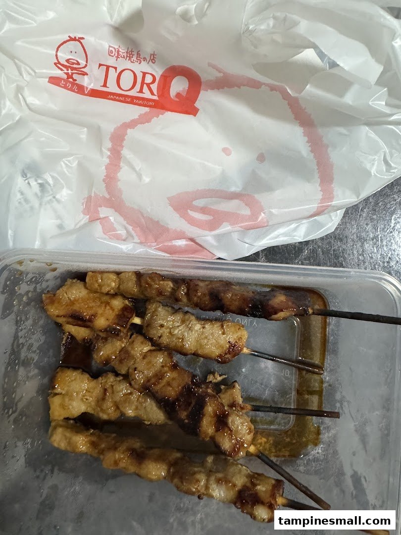Delicious yakitori skewers in a takeaway container with a TORI-Q branded bag.