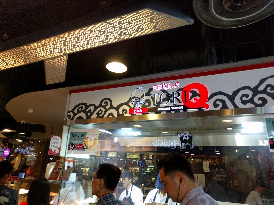 Customers queueing at the counter of TORI-Q, a Japanese yakitori shop, with its prominent signage.