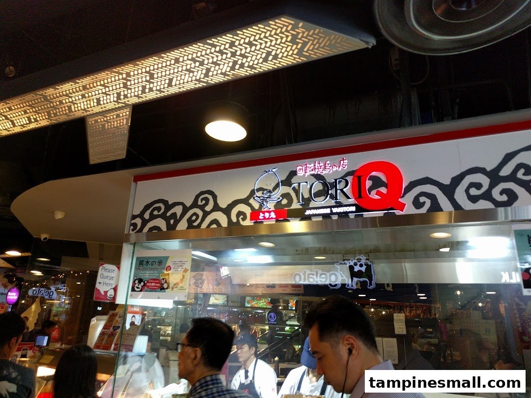 Customers queueing at the counter of TORI-Q, a Japanese yakitori shop, with its prominent signage.