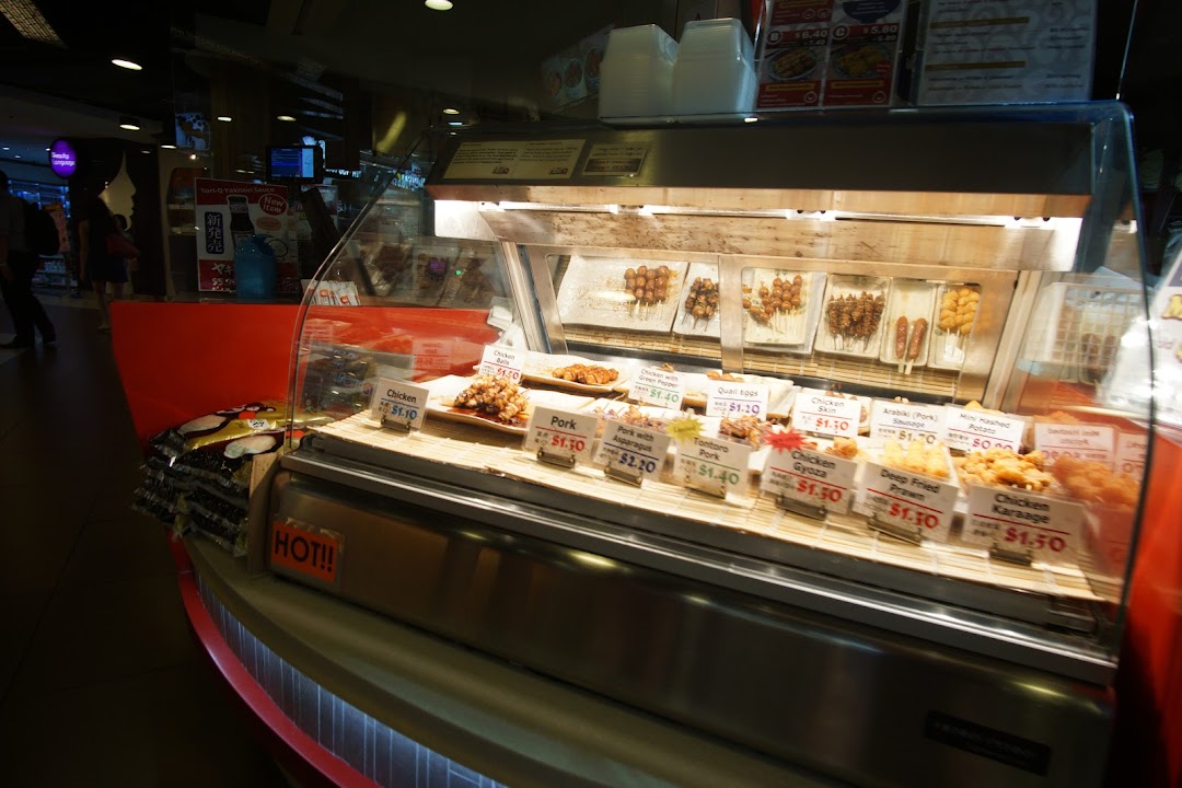 A vibrant display case showcasing a variety of Japanese skewers and fried items with price tags.