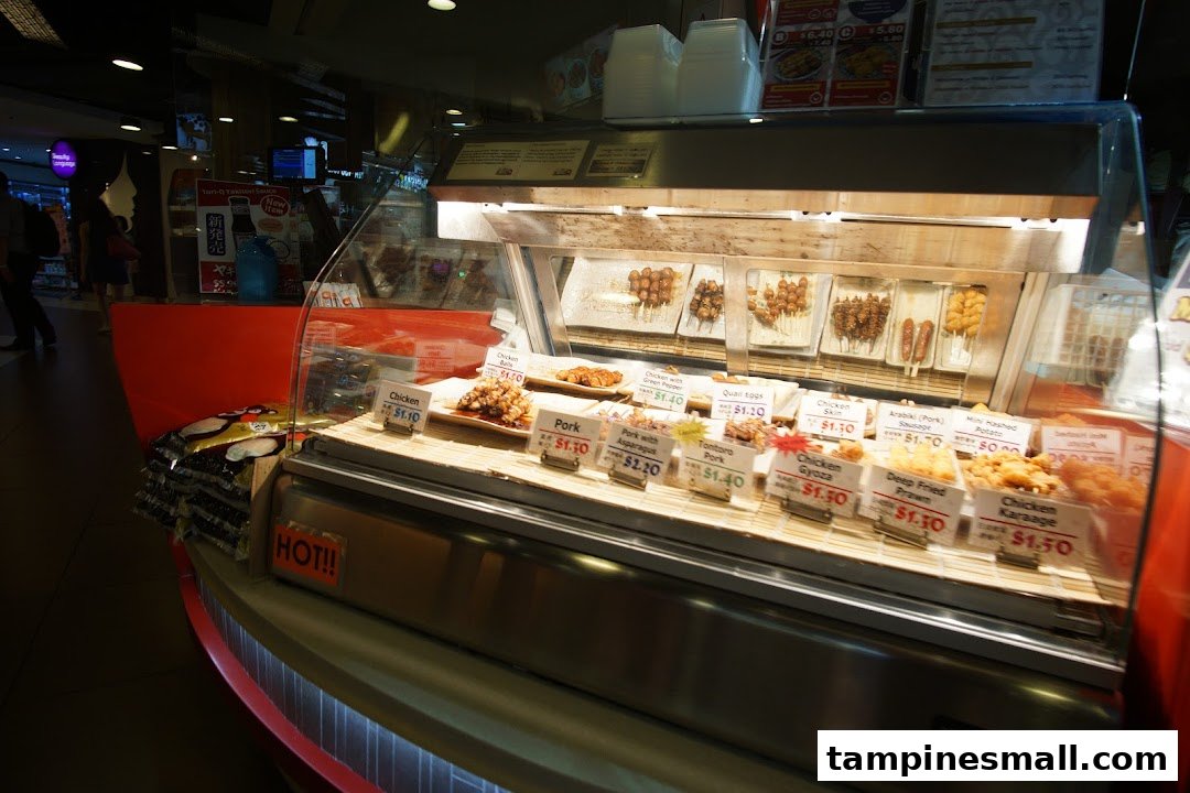 A vibrant display case showcasing a variety of Japanese skewers and fried items with price tags.