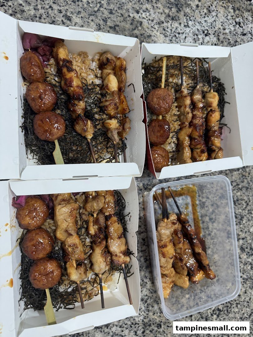 Multiple bento boxes filled with grilled skewers, meatballs, and rice, ready for takeaway.