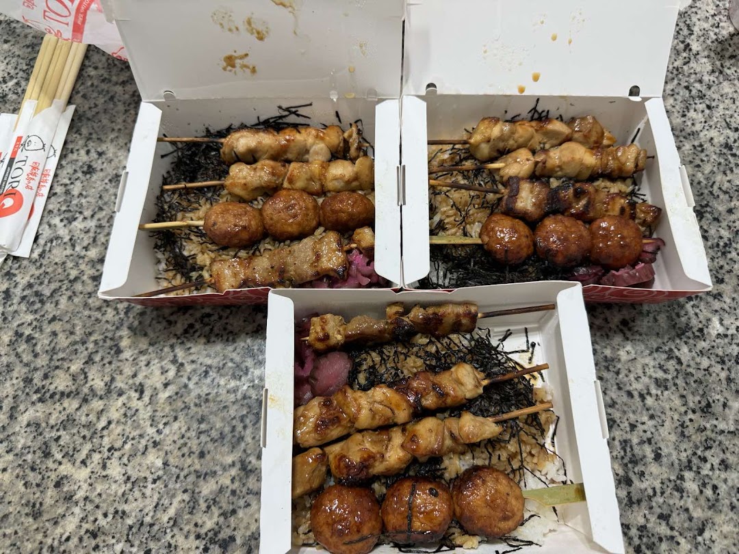 Three bento boxes filled with grilled yakitori skewers, rice, and seaweed, ready for takeaway.