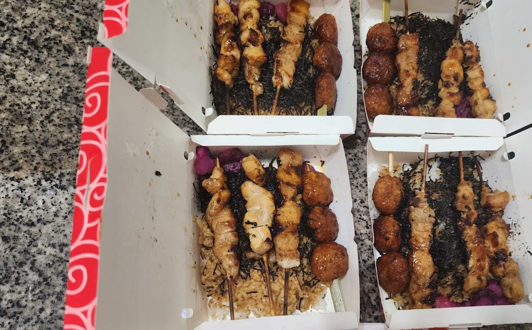 Multiple open takeaway boxes filled with various grilled skewers, rice, and toppings from TORI-Q.