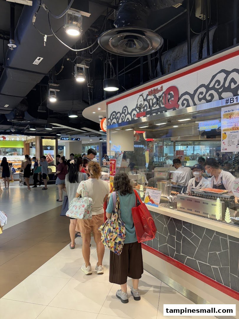 Customers queueing at the TORI-Q counter, with staff preparing food in the background.