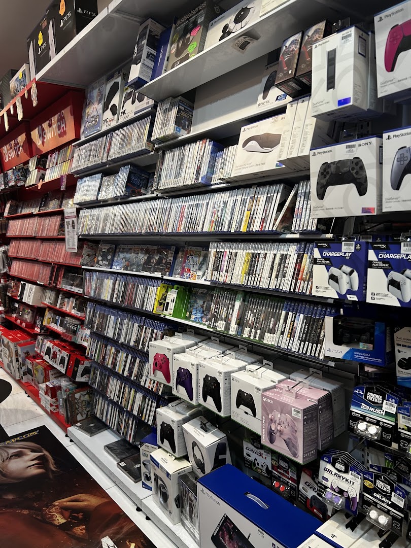 Shelves filled with a vast collection of video games, consoles, and gaming accessories in a retail store.