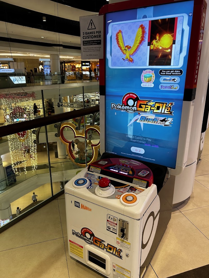 A Pokémon Ga-Olé arcade game machine stands ready for play in a bustling shopping mall.