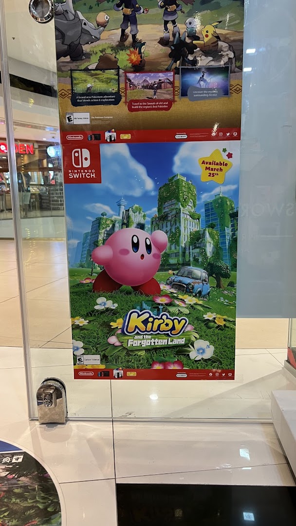 Promotional posters for Nintendo Switch games, including Kirby and Pokémon, displayed inside a retail shop.