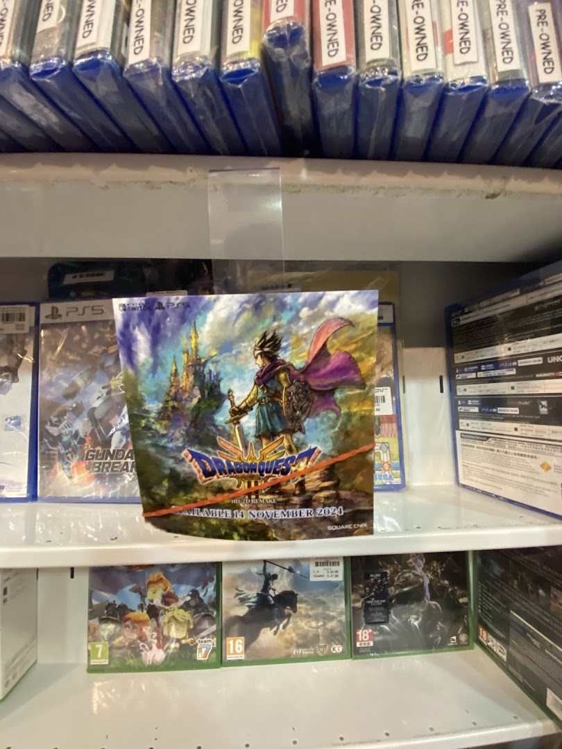 Shelves filled with video game cases, including a prominent Dragon Quest poster, in a retail shop.