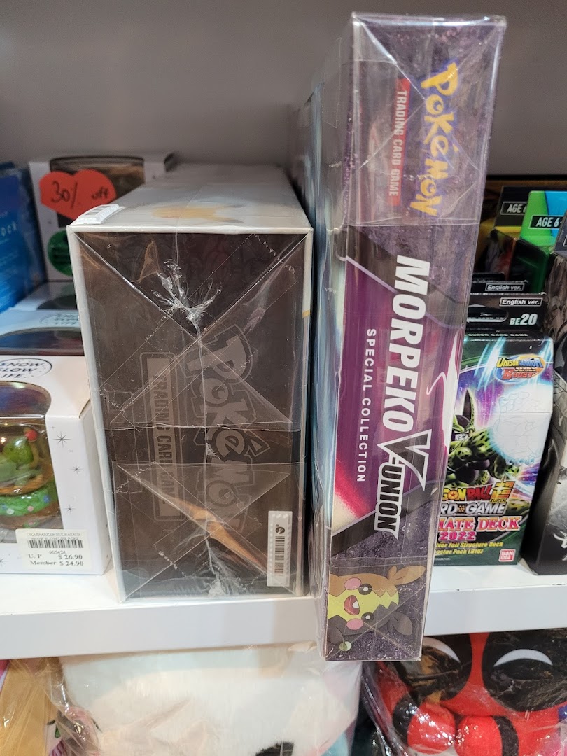 Close-up of Pokémon Trading Card Game boxes and other packaged merchandise on a retail shelf.