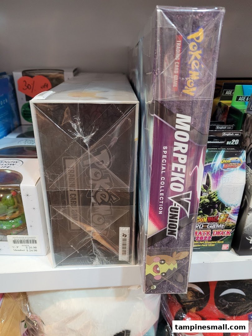 Close-up of Pokémon Trading Card Game boxes and other packaged merchandise on a retail shelf.