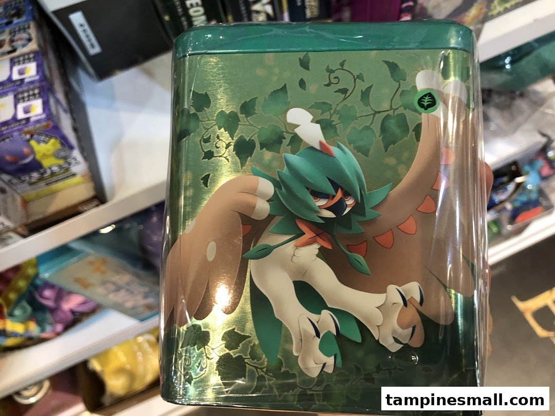 Close-up of a green Pokémon-themed tin featuring Decidueye, displayed in a toy or game shop.