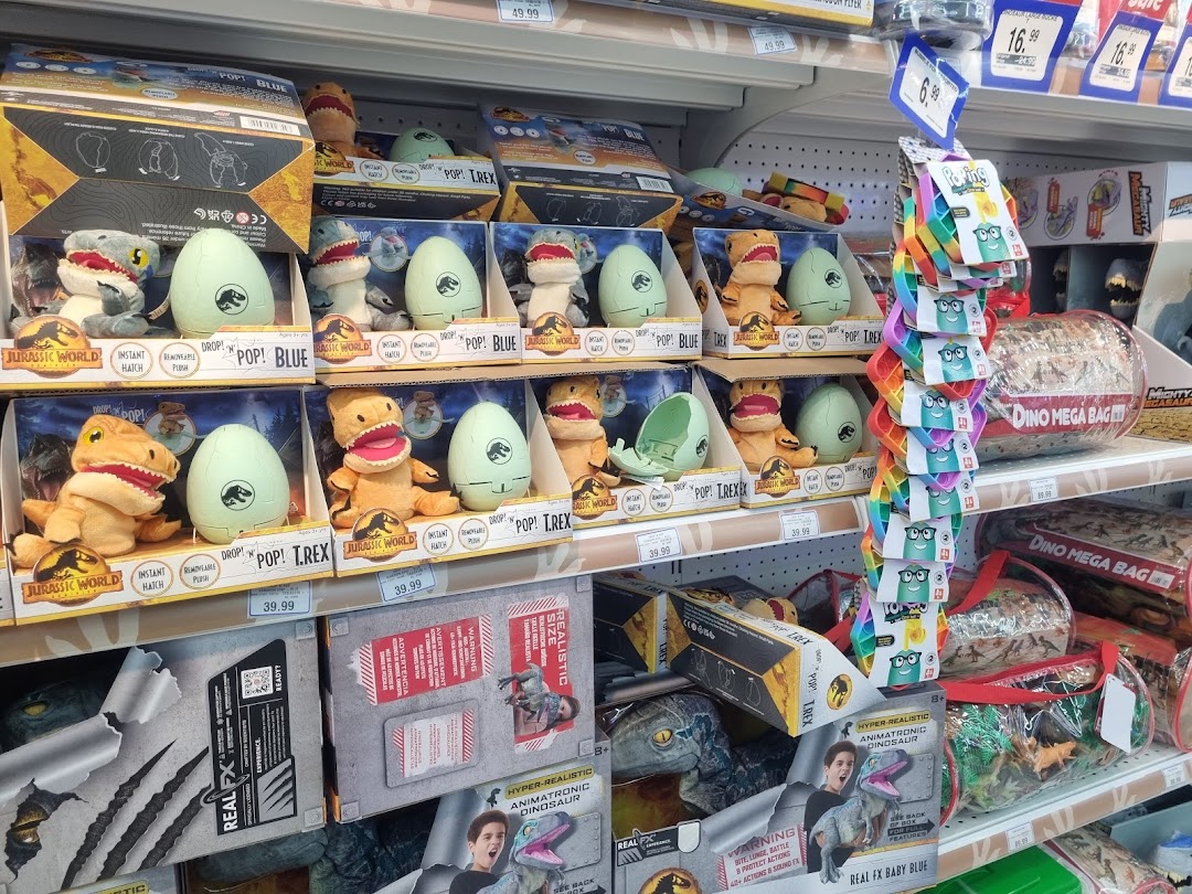 Shelves at ToysRUs filled with Jurassic World dinosaur plush toys and other related merchandise.