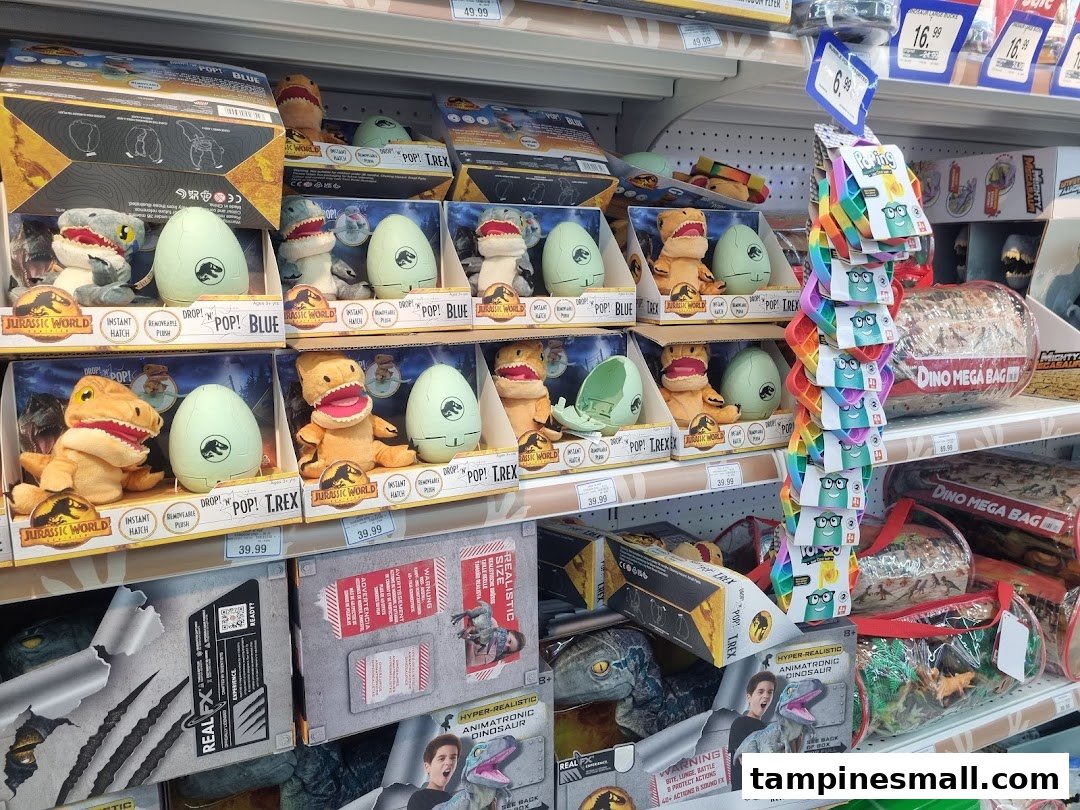 Shelves at ToysRUs filled with Jurassic World dinosaur plush toys and other related merchandise.
