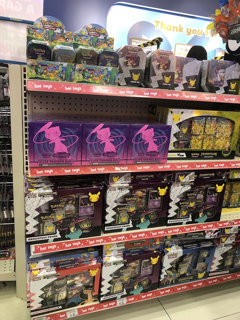 Shelves at ToysRUs filled with various Pokémon Trading Card Game products, including Elite Trainer Boxes.