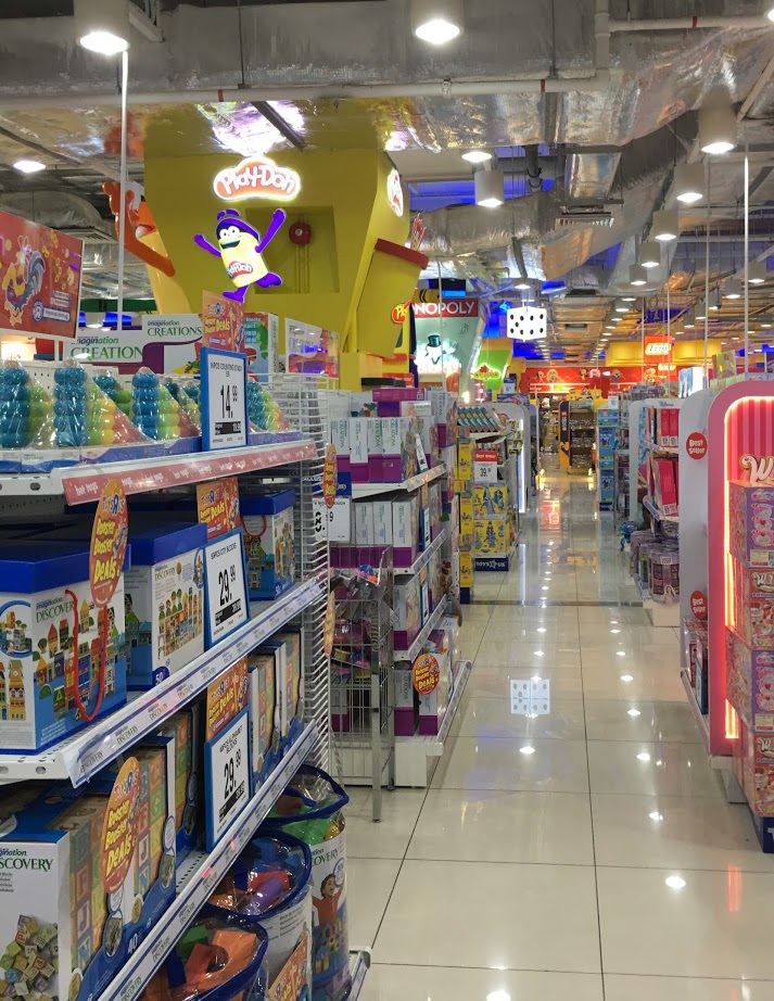 An interior view of ToysRUs, showcasing brightly lit aisles filled with a wide variety of toys and games.